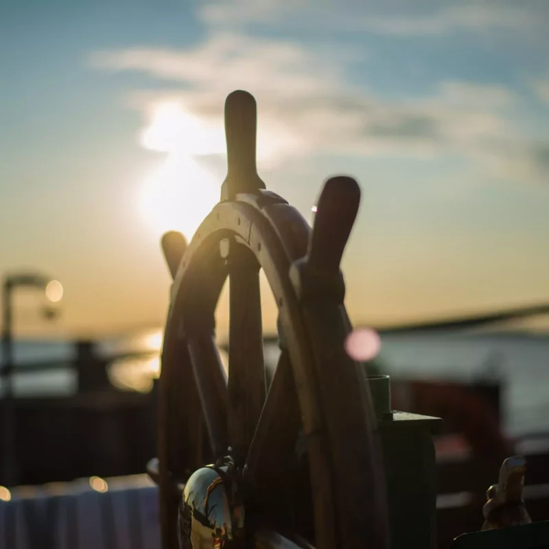 Steuerrad eines Schiffs im Gegenlicht bei Sonnenuntergang